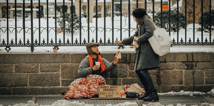 Personne sans domicile fixe discutant avec une passante dans une rue en hiver