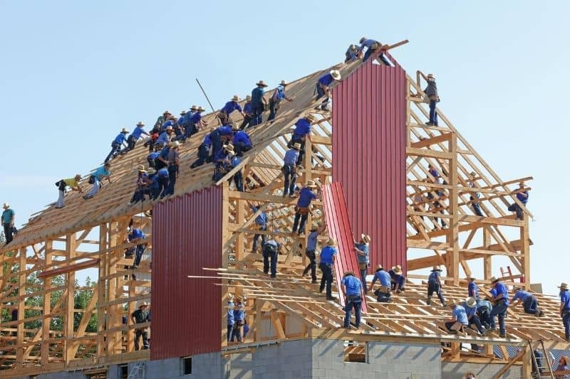 personnes collaborant pour construire un large bâtiment