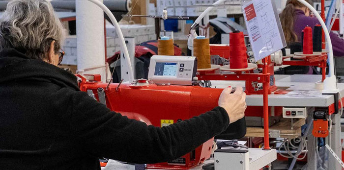 Personne de dos utilisant une machine rouge pour fabriquer un jean