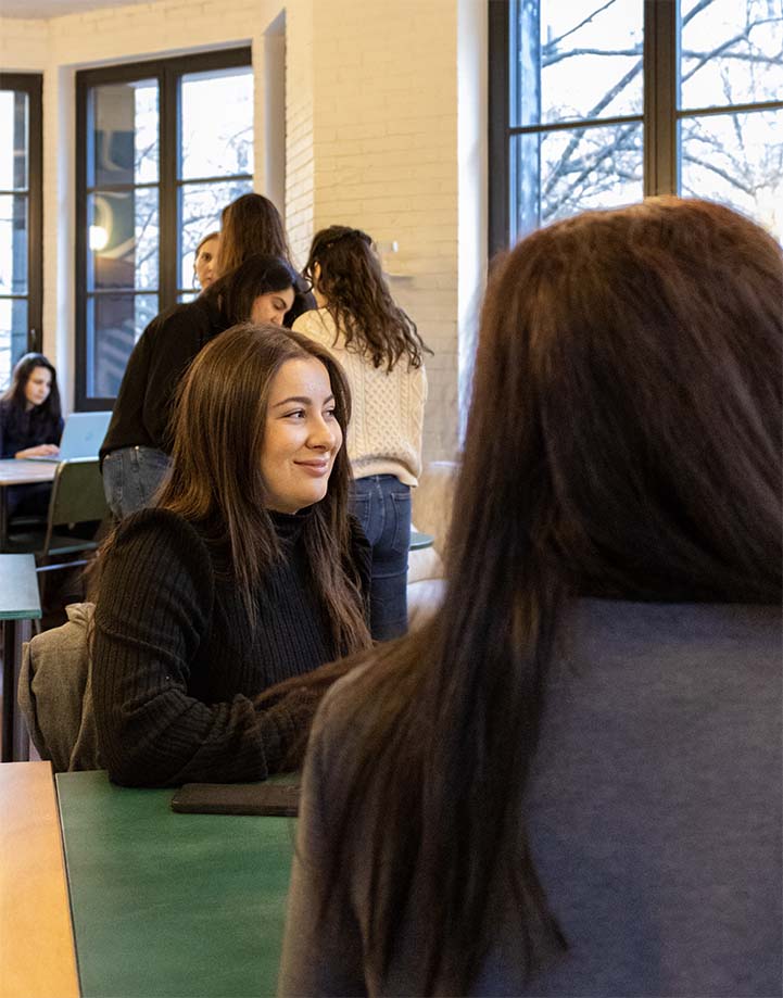 Etudiante en pull noir, regarde à droite et sourit