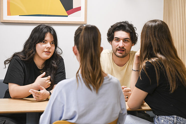 Quatre étudiants discutent ensemble autour d'une table Quatre étudiants discutent ensemble autour d'une table