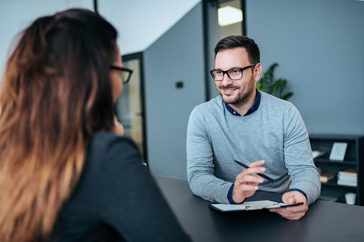 Homme brune en pull gris avec des lunettes noires parle avec une femme de dos Homme brune en pull gris avec des lunettes noires parle avec une femme de dos