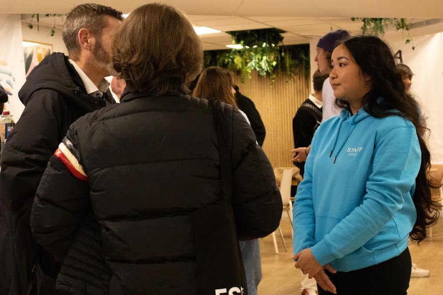 Femme brune en pull bleu discute avec deux hommes Femme brune en pull bleu discute avec deux hommes